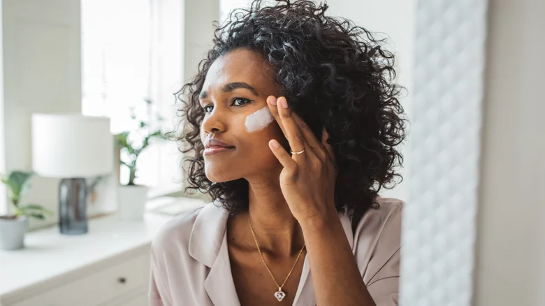 woman putting cosmetics on her face | geria dermatology