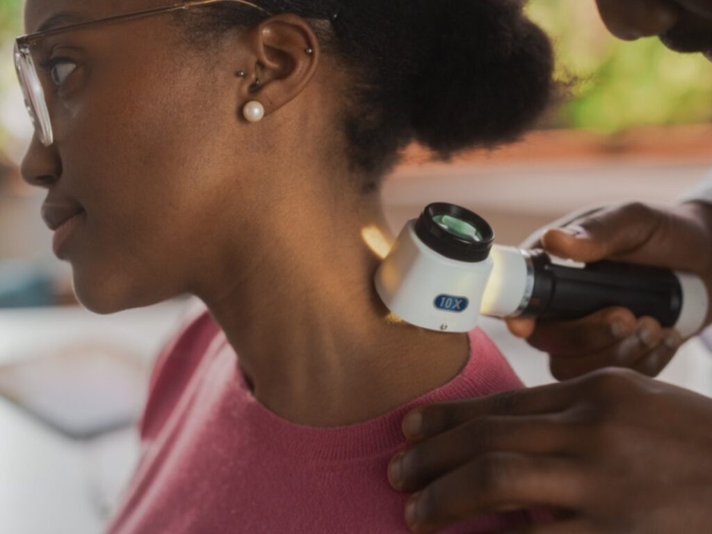 Dermatologist examining a patient’s neck with a dermatoscope during a skin cancer screening before Mohs surgery. Dermatologist examining a patient’s neck with a dermatoscope during a skin cancer screening before Mohs surgery.